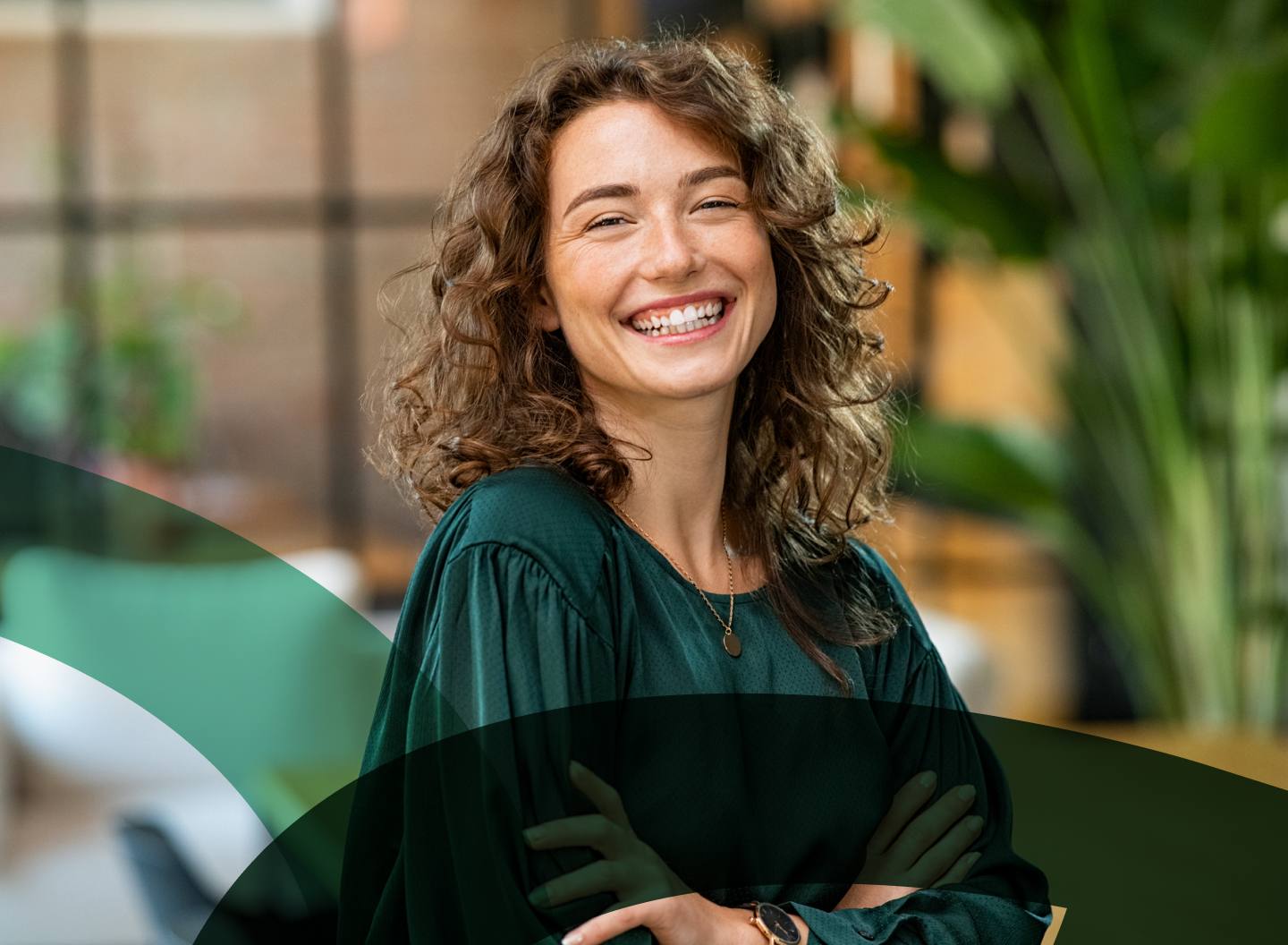 Smiling professional woman in a green blouse standing confidently in an office.