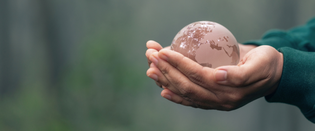 Hands holding a glass globe representing global support and care.