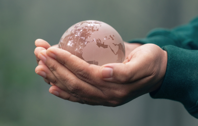 Hands holding a glass globe representing global support and care.