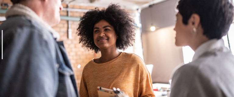 Three colleagues engage in a supportive conversation at the workplace.