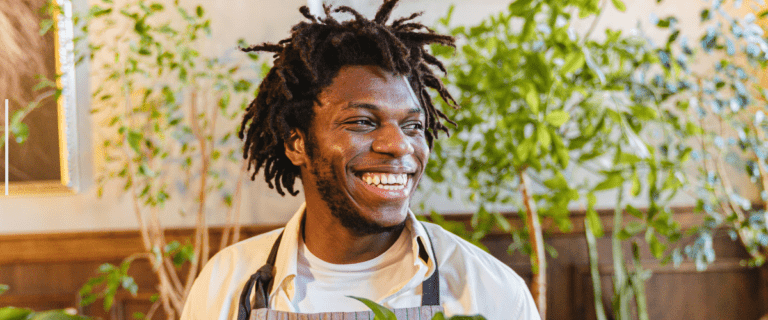 Employee smiling joyfully in a lush office environment surrounded by greenery.